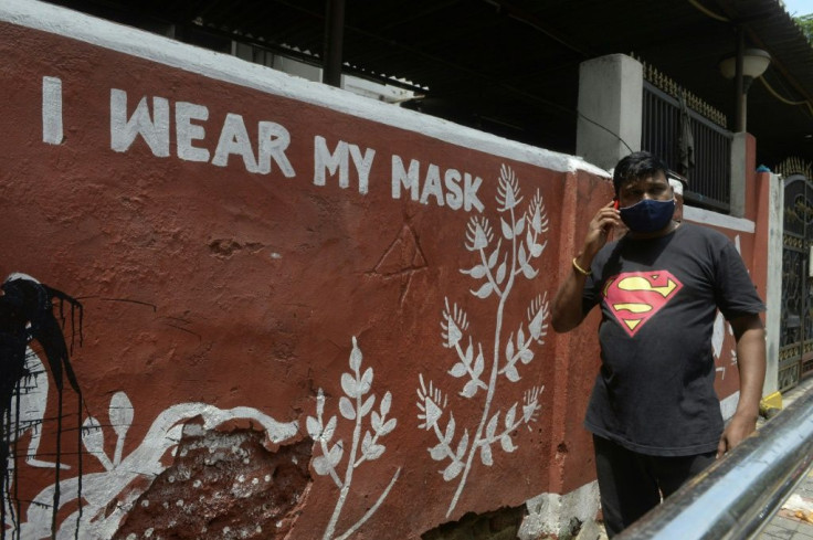 A man walks past a mural with a message spreading awareness about Covid-19 in Hyderabad