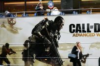 A woman walks past a bus advertising video game "Call of Duty" made by Activision Blizzard, which is being accused of workplace harassment of female employees