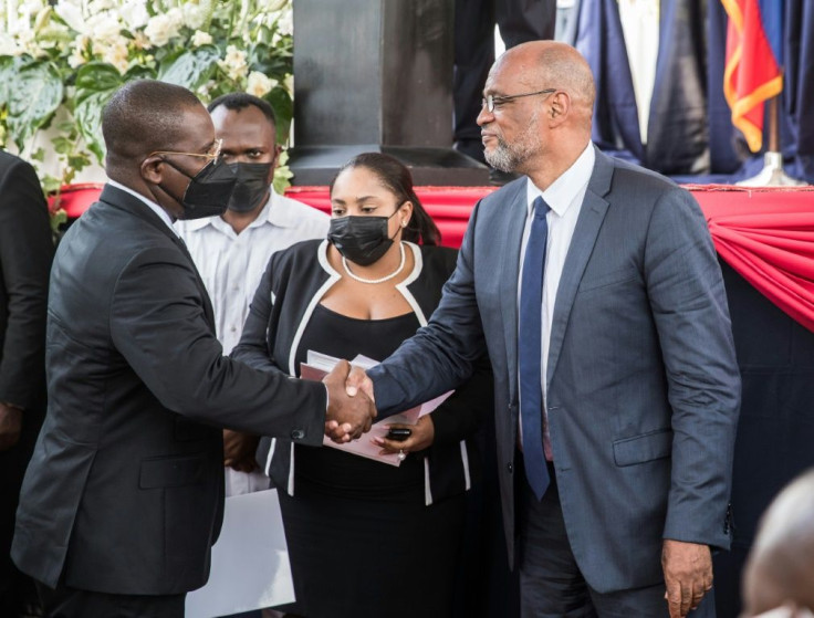 Haiti's new prime minister Ariel Henry (R) shakes hands with his predecessor Claude Joseph, who led the country in the wake of Jovenel Moise's assassination