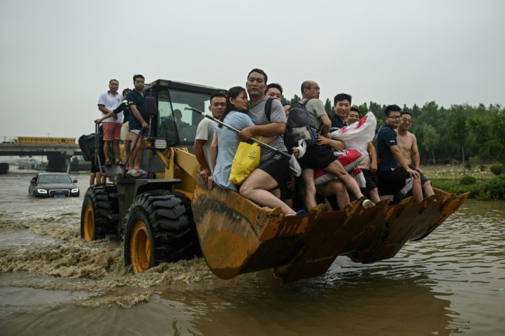 People are carried across a flooded street in the worst-hit city of Zhengzhou, which received a year's worth of rain in just three days