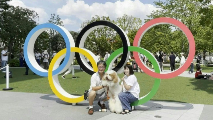 Hours ahead of the opening ceremony of the Tokyo 2020 Olympics, people take photos outside the Olympic Stadium.