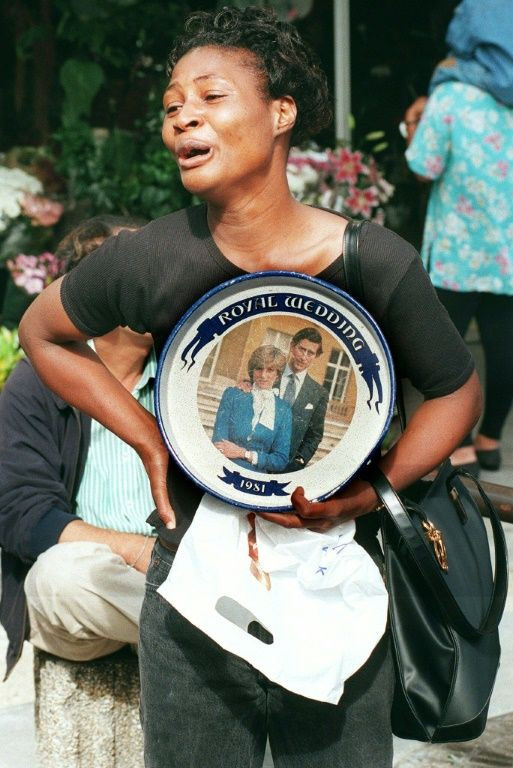 A woman holding a plate commemorating the wedding of Prince Charles and Princess Diana mourns on August 31, 1997, in Paris after Diana's death in a car crash