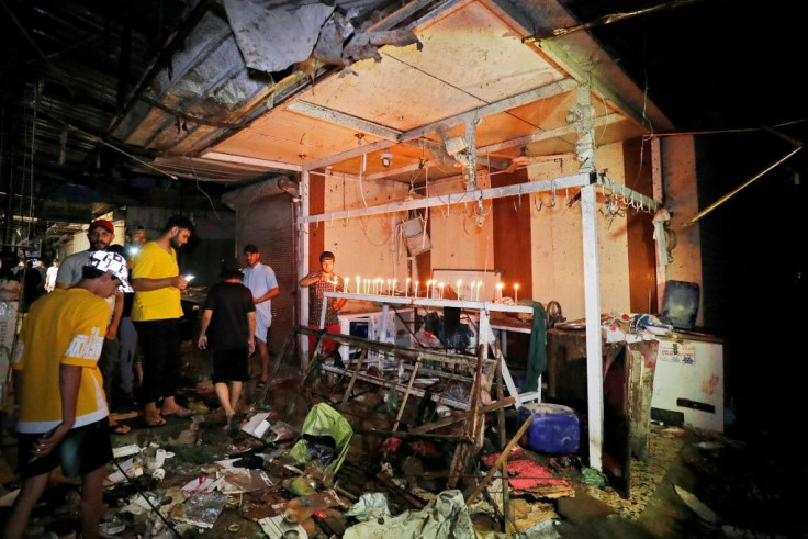 Iraqis light candles at the site of the explosion in a popular market in the mostly Shiite neighbourhood of Sadr City, east of Baghdad, on July 19, 2021