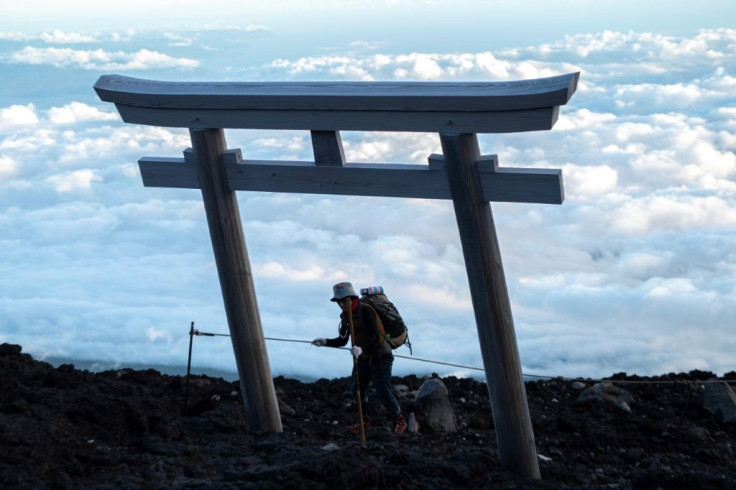 Climbers at the summit can watch it breaking through the clouds behind a traditional "tori" gate on the mountainside