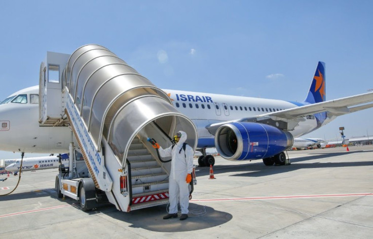 An Israeli worker in full hazmat suit sprays disinfectant on the stairs of an Israir airplane at Ben Gurion airport near Israel's Tel Aviv, in this file picture taken on June 14, 2020, amid the Covid-19 pandemic