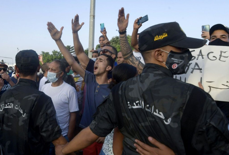 Tunisian security officers hold back supporters of President Kais Saied as they chant slogans against the country's largest political party near parliament on Monday