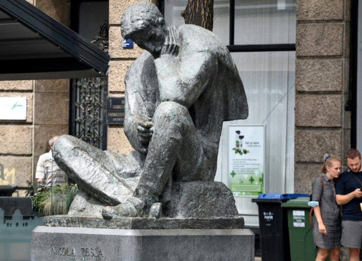 People walk past a bronze statue of inventor and engineer Nikola Tesla, on July 26, 2021 in Zagreb