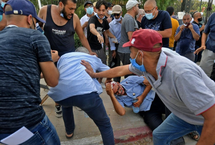 A supporter of the country's Islamist Ennahdha party (on the ground C) is injured by a stone thrown at him during a protest outside the parliament building in the capital Tunis on Monday