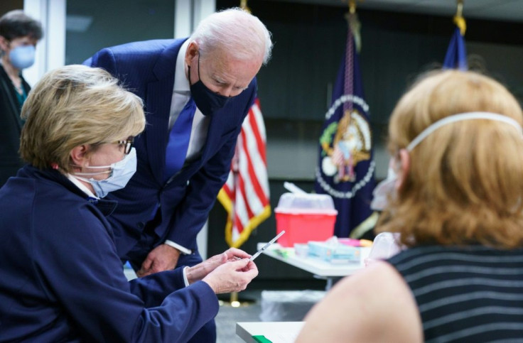 US President Joe Biden looks at a dose of vaccine before its administered at a Covid-19 vaccination site at the Washington DC Veterans Affairs Medical Center in Washington