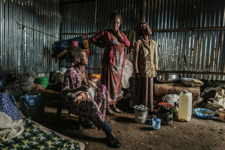 Eritrean refugee Seble Melkamu (left) cuddles her son as she talks with other refugees in her shelter at a camp in the town of Azezo