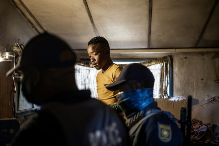 Police go through a home at the Nguni Hostels in the Johannesburg suburb of Vosloorus, looking for goods looted from a nearby shopping mall