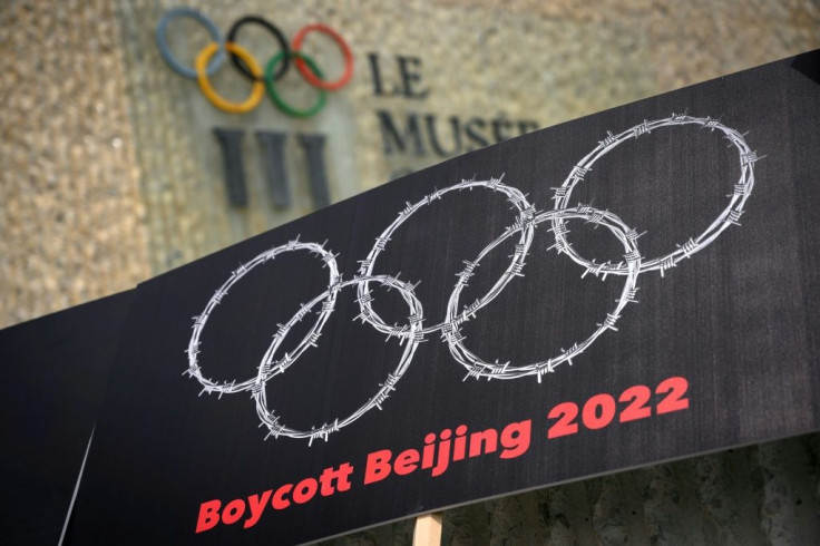 Tibetan and Uyghur activists hold up a placard showing the Olympic rings as barbed wire during a June 2021 protest outside the Olympic Museum in Lausanne, Switzerland