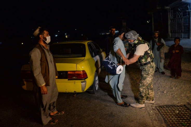 Afghan security force personnel searching a commuter at a checkpoint in Herat, western Afghanistan