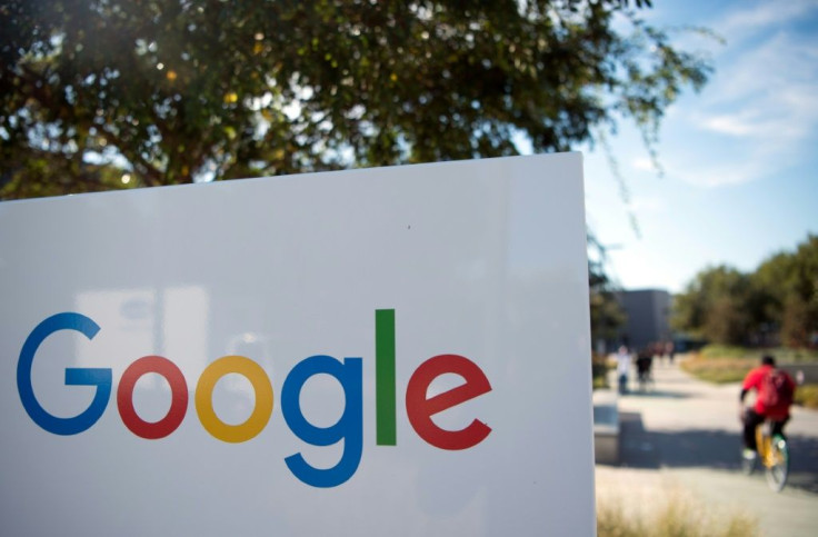 A man rides a bike passed a Google sign and logo at the Googleplex in Menlo Park, California on November 4, 2016