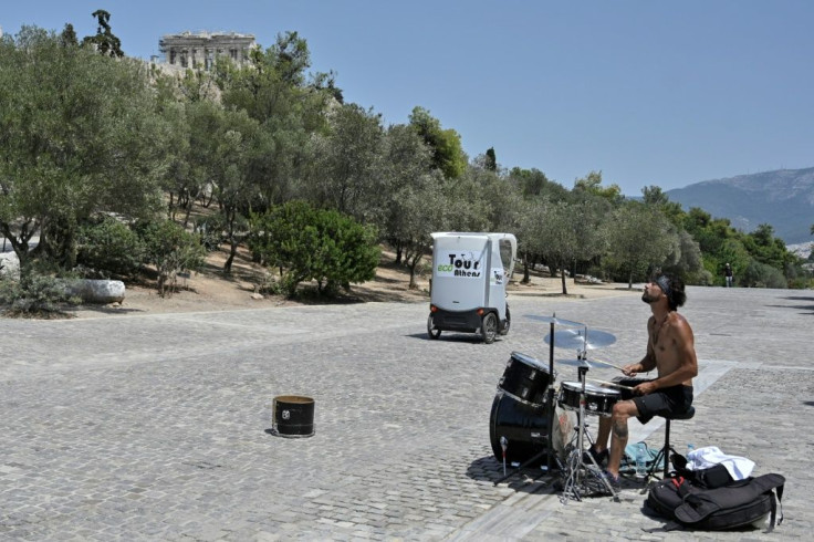 A street musician plays drums during a heatwave in Athens