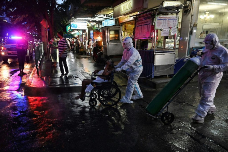 An elderly Covid-19 patient is taken away from his home by medics in Bangkok to be treated in hospital