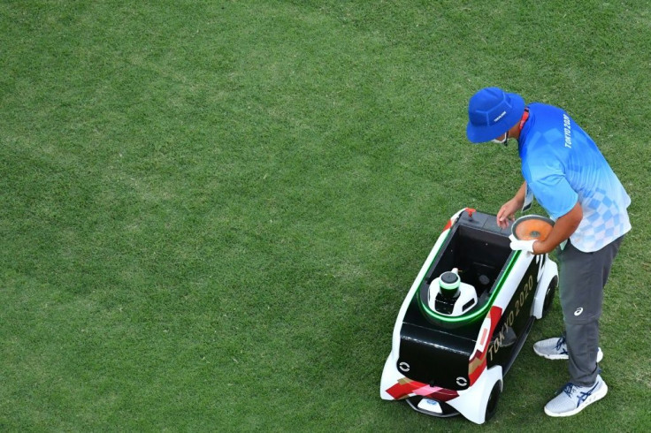 A volunteer puts a discus into a remote-controlled car at the Tokyo Olympics