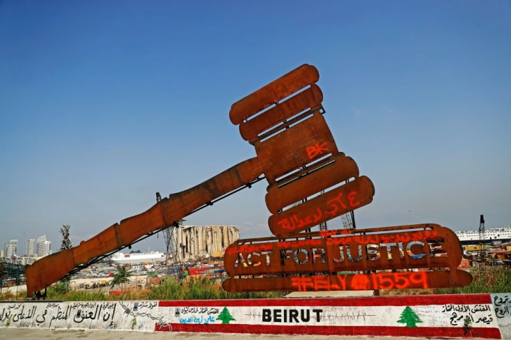 A gavel monument symbolising justice is seen in front of the damaged grain silos at Beirut port on August 4, 2021, the one year anniversary of the powerful blast