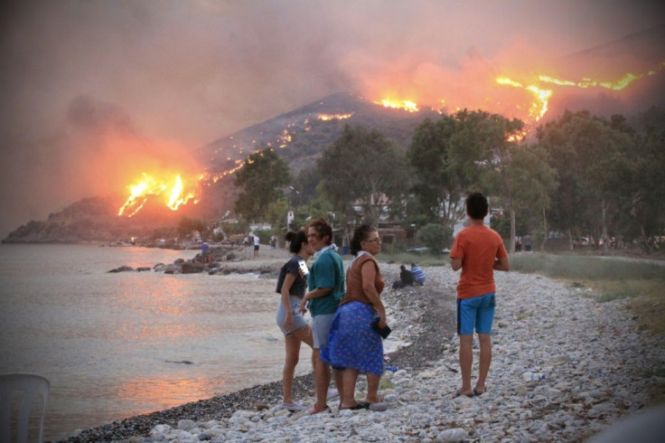 Local people watch the fires from the relative safety of the beach in the Aegean coast city of Oren, near Milas