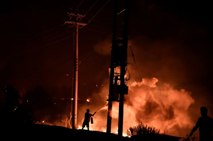 A man uses a fire extinguisher as local residents try to fight a forest fire in Dekelia, north of Athens