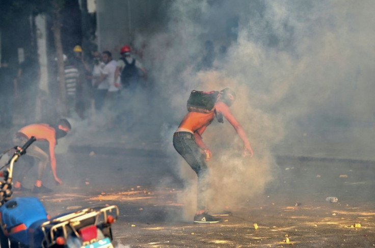 A demonstrator returns a teargas cannister as Lebanese army and security forces clash with protesters near parliament in downtown Beirut on the first anniversary of the deadly blast that ravaged the port and the city