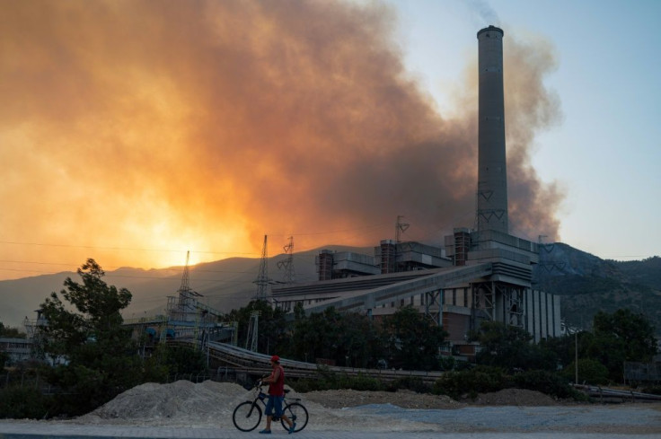 A man pushes a bike along a road in the vicinity of a forest fire close to the Kemerkoy Thermal Power Plant in northen Turkey