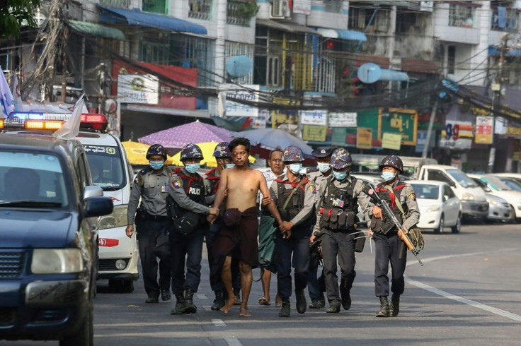 Police in Yangon in February 2021 march with a resident arrested during a crackdown on protesters holding rallies against Myanmar's military coup