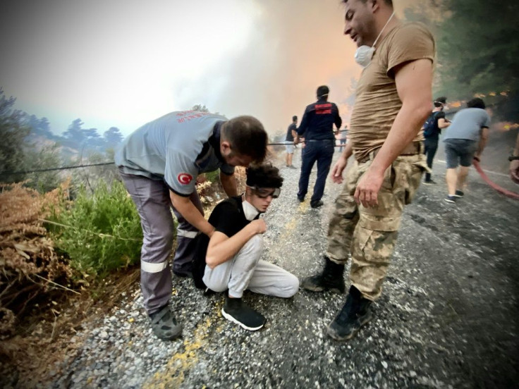 A youth receives assistance as firemen and local volunteers fight to extinguish a wildfire in Oren in Turkey