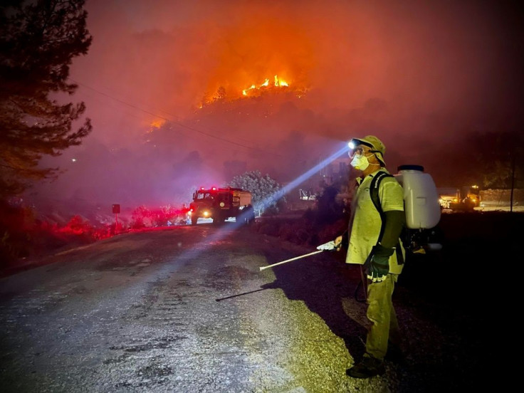 Firemen, assisted by local volunteers, fight to extinguish a wildfire in Oren in Turkey