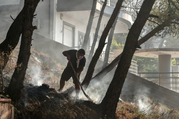 A local resident fights a fire flare-up north of Athens