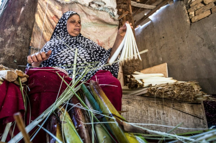 A woman slices papyrus into thin strips at the workshop in al-Qaramus