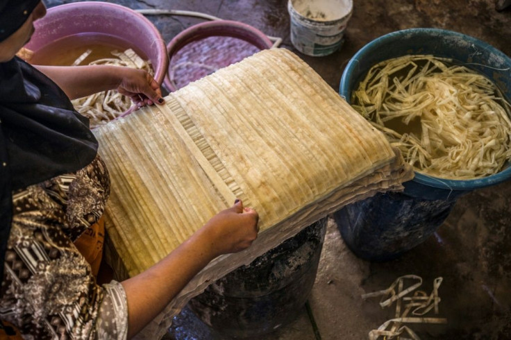 A woman lays out soaked thin strips of papyrus to form a sheet, before compression and drying at the workshop
