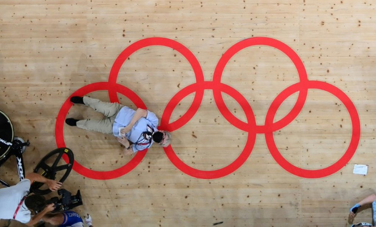 An official lies on the track after being knocked over by cyclists