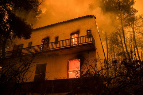 A house burns as fires approach the village of Pefki on Evia