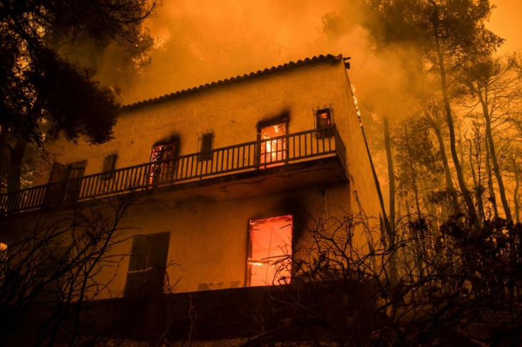 A house burns as fires approach the village of Pefki on Evia