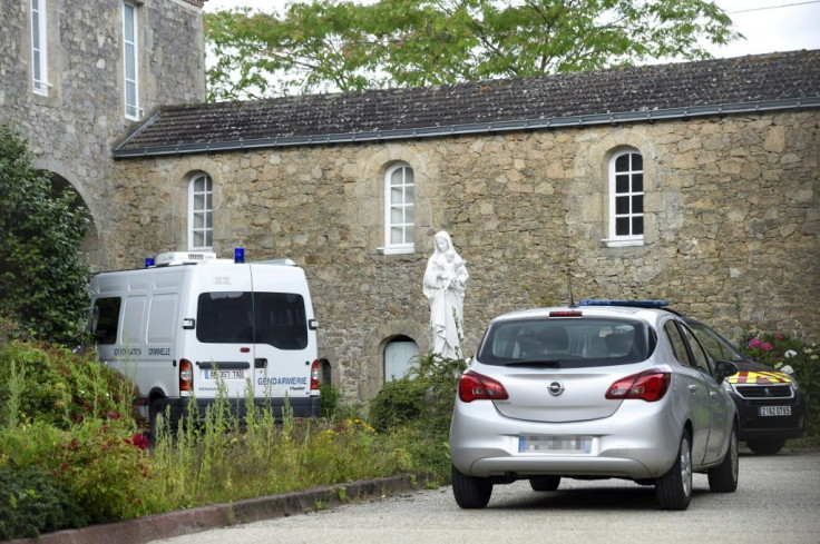 French police vehicles are parked where a French Catholic priest, aged 60, was murdered in Saint-Laurent-sur-Sevres, western France