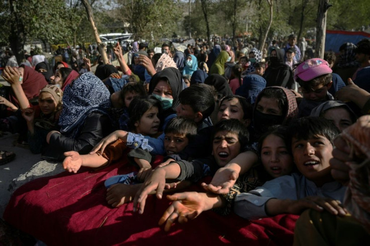 Afghan families who fled Kunduz and Takhar provinces due to battles between Taliban and Afghan security forces collect food in Kabul
