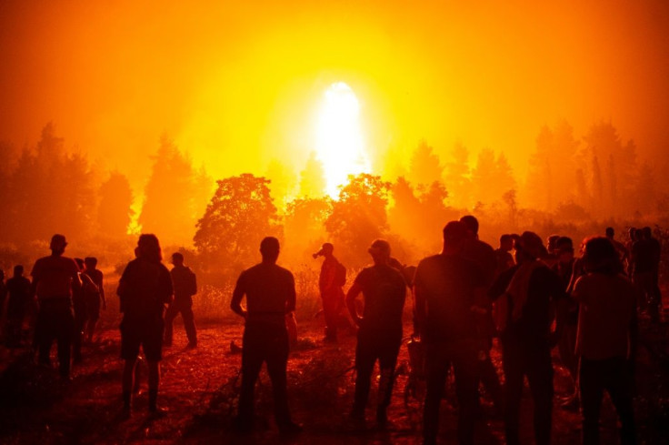 Local youths and volunteers gather in an open field and wait to support firefighters during a wildfire on Evia (Euboea) island, Greece