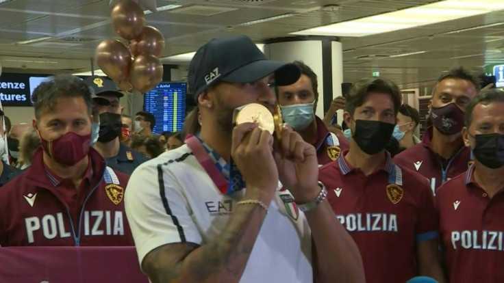 Dozens of fans, family and friends, are on hand inside Rome's Fiumicino airport to greet Italy's returning athletes, erupting into cheers at the sight of Lamont Marcell Jacobs.