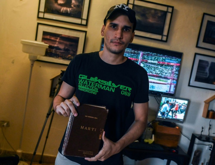Rolando Remedios holds a book by Cuban idol Jose MartÃ