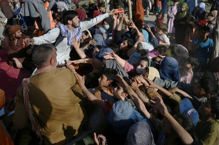 People clamour for snacks being handed out by a volunteer at a camp for displaced people in Kabul