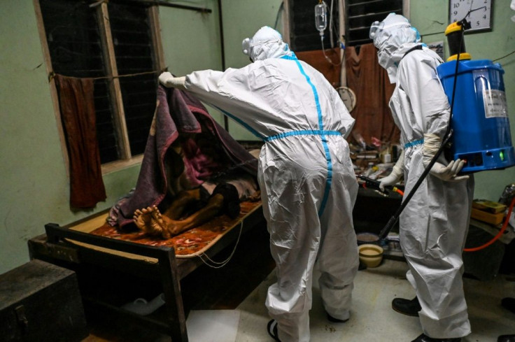 Volunteers disinfect the body of a monk suspected of dying of Covid-19 coronavirus at a monastery, before transferring him to a crematorium
