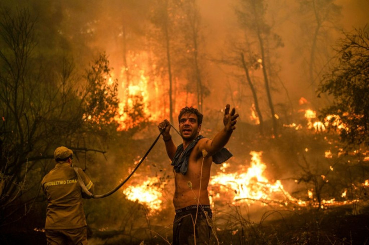 An islander holds an empty water hose during an attempt to extinguish forest fires approaching the Evia island village of Pefki
