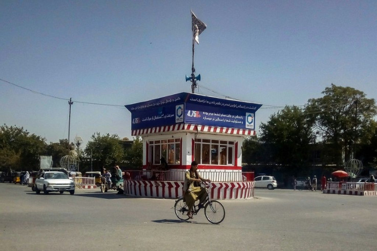 A cyclist rides past a booth with a Taliban flag in the main square of the northern city of Kunduz on August 9, 2021, after it was captured by the insurgents
