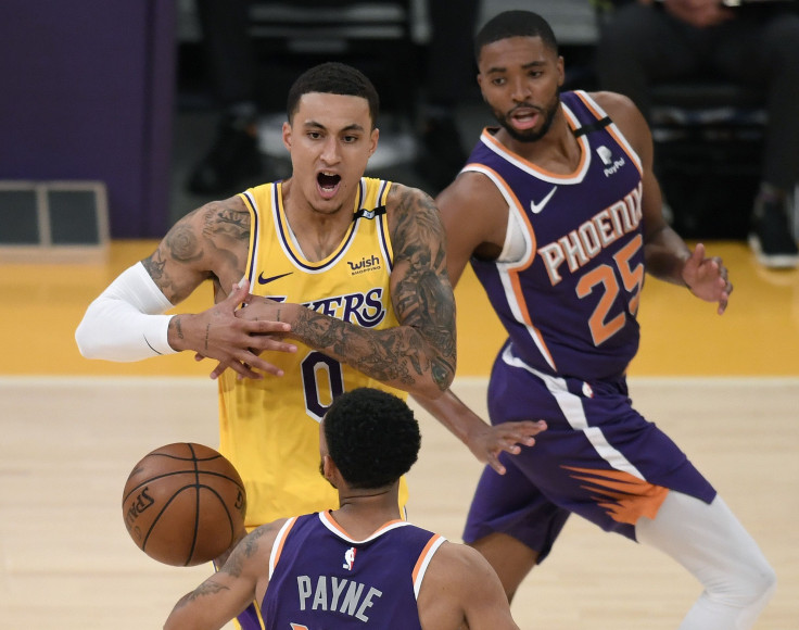 Kyle Kuzma #0 of the Los Angeles Lakers reacts as he loses the ball between Cameron Payne #15 and Mikal Bridges #25 of the Phoenix Suns