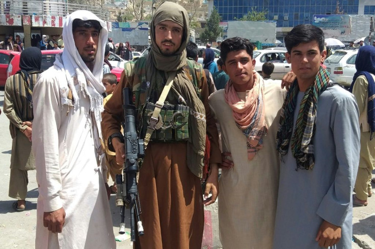 A Taliban fighter poses with locals in Pul-e-Khumri, the capital of Baghlan province