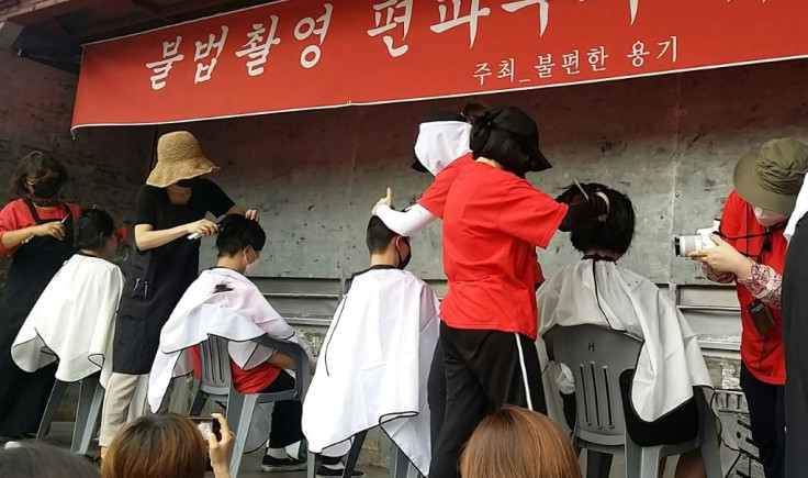 Women shave their heads at a protest against spycam crime