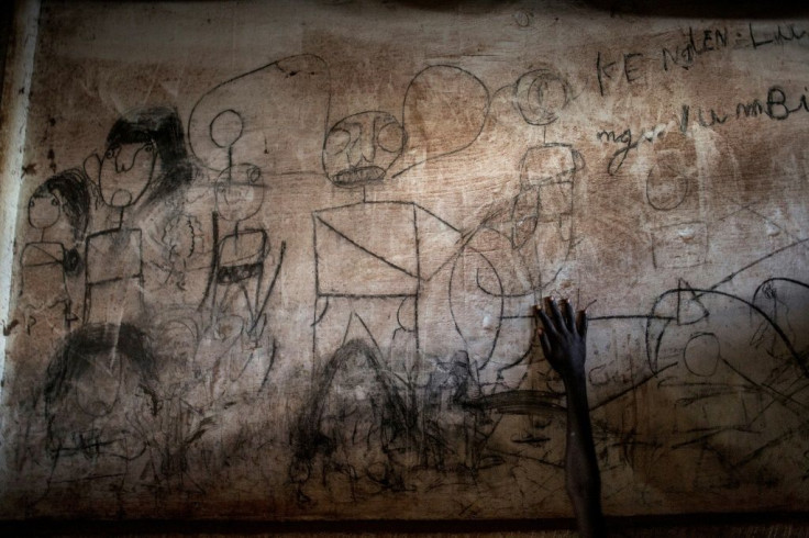 The hand of a young South Sudanese refugee at a camp in DR Congo is seen on a wall filled with drawings and writings depicting scenes from home (2019 file picture)
