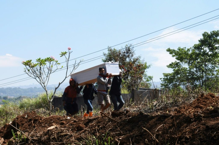 Gravediggers carry a coffin of a Covid-19 coronavirus victim in Indonesia as the pandemic's toll continues to rise