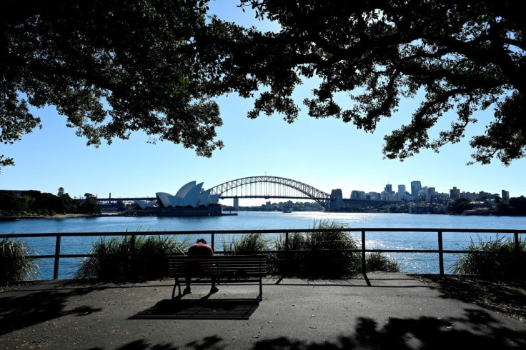 A man sits in front of the Harbour Bridge and Opera House in Sydney. People are still allowed out for exercise, shopping, health care and essential work